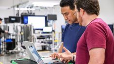 Image of two men speaking together, gesturing a computer screen.