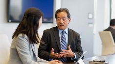 Image of a man and a woman sitting in front of an open computer talking to each other.
