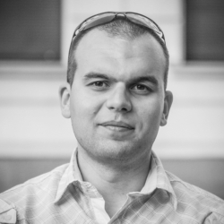 a man wearing glasses and smiling at the camera