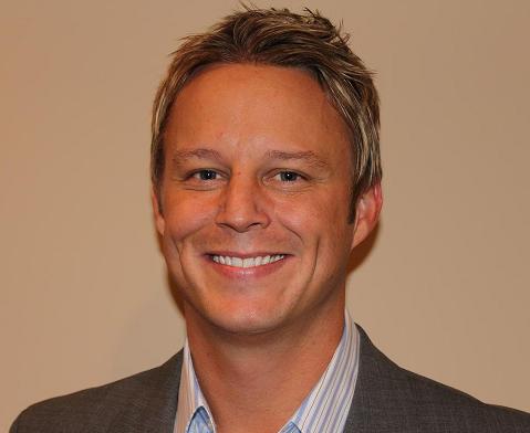 David Pennington wearing a suit and tie smiling at the camera