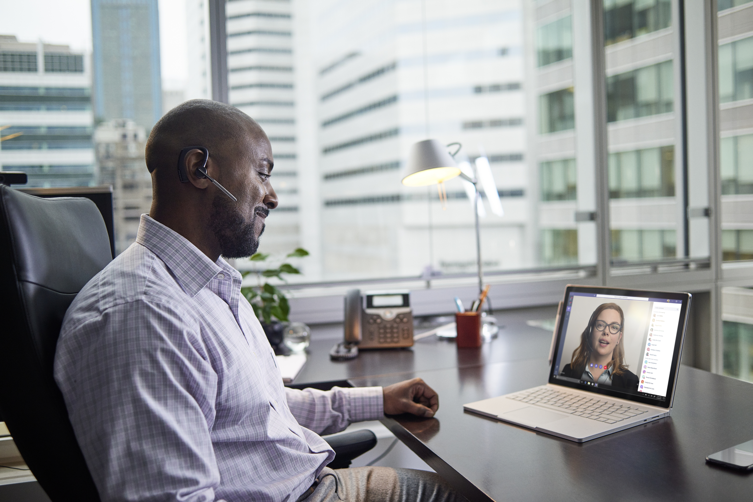 Male business executive working on a Surface Pro Book at desk, running Microsoft Teams.