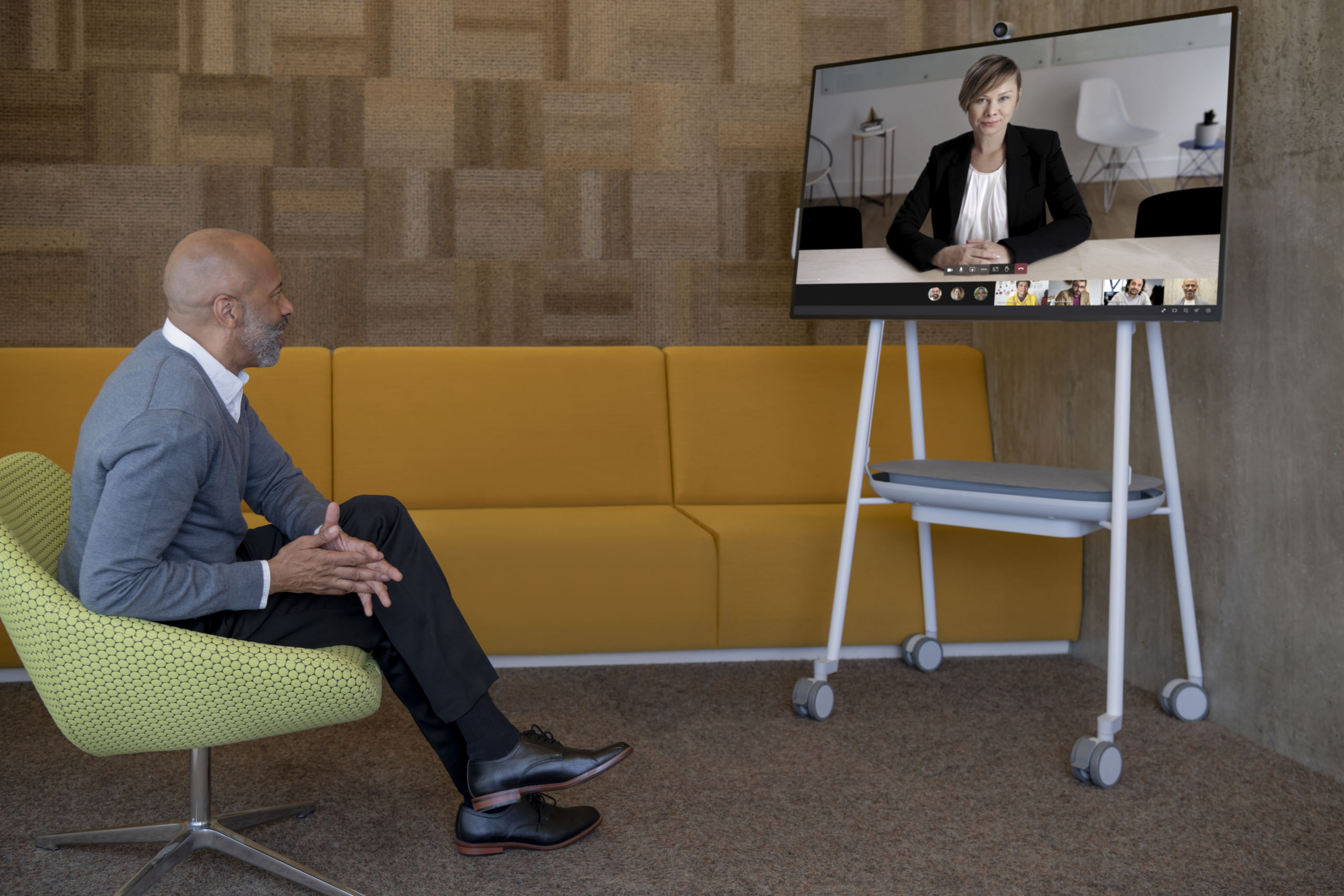 Adult male in his office collaborating with a woman via Microsoft Teams on a Surface Hub 2S 50&rdquo; device. Expires 11/25/2022