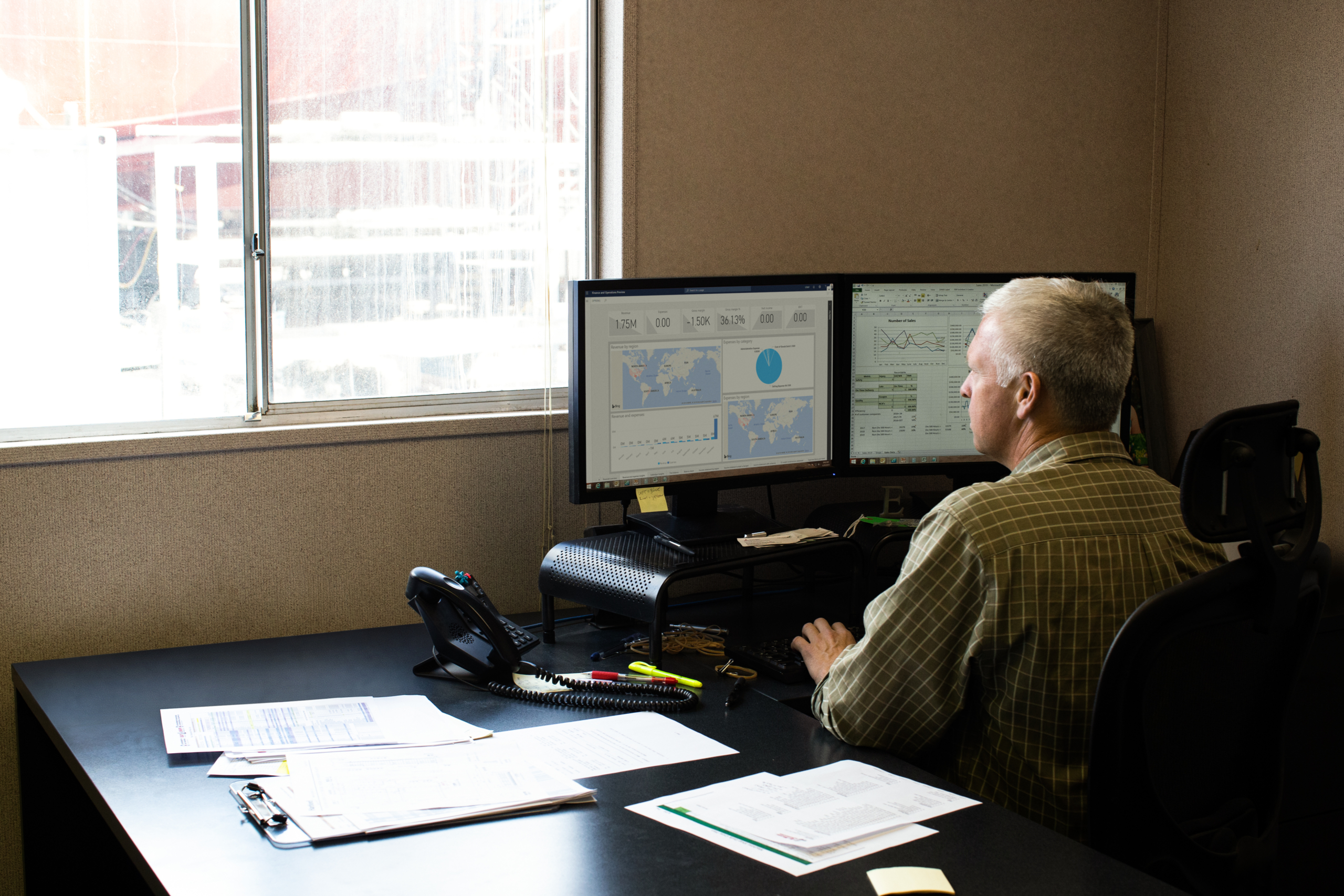 Operations manager at work in his office; shipyard is outside his window.