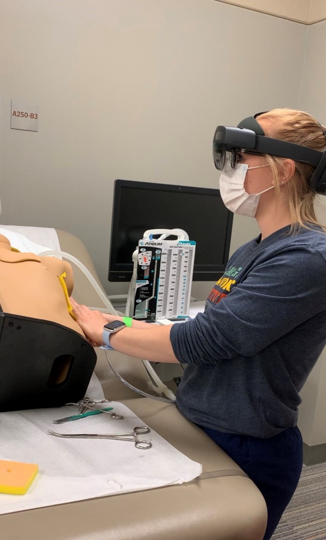 A nursing student practicing a catheterization procedure on a mannequin with HoloLens 2.