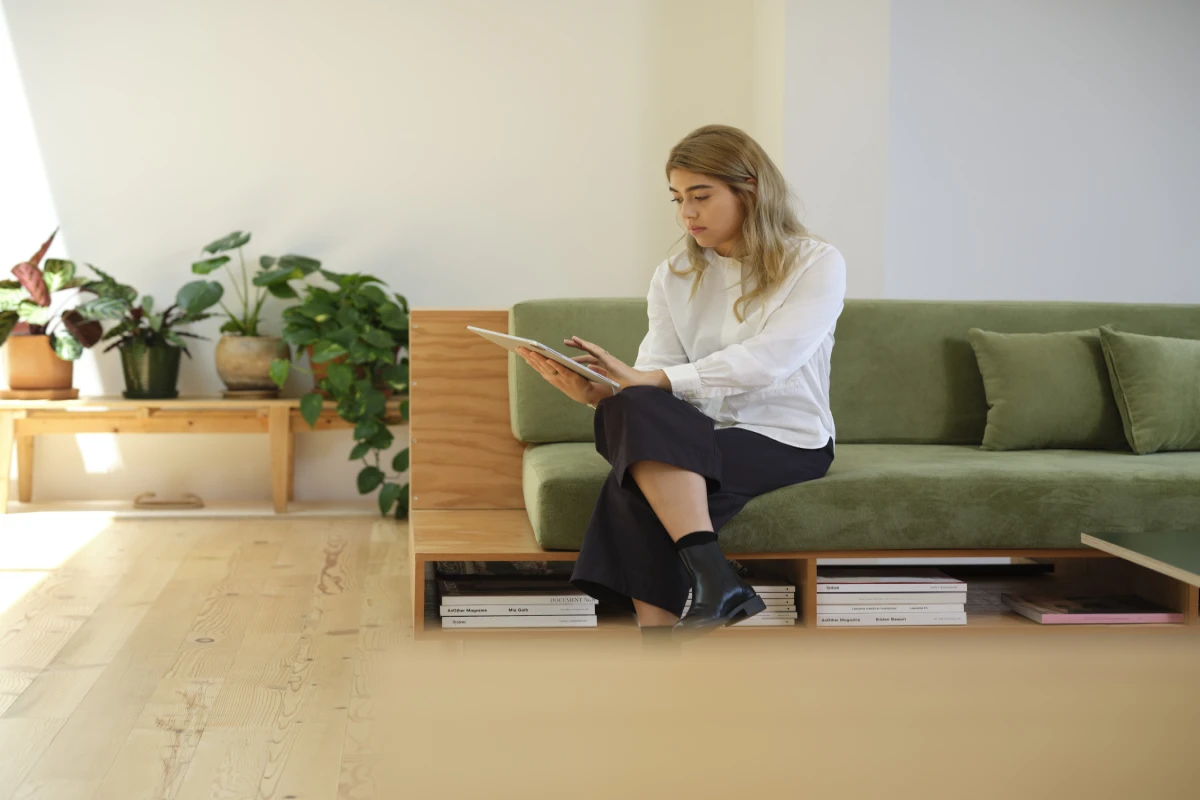 A female architect sitting on a green couch using a Surface tablet.