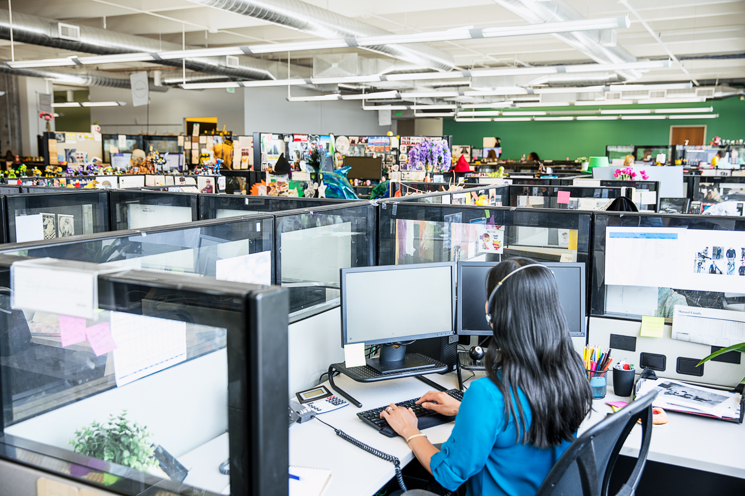 Photo of a female call center employee working at a cubicle desk.