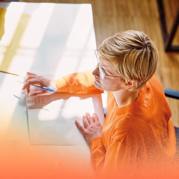Overhead view of an adult businesswoman with notebook sitting at a desk in an office.