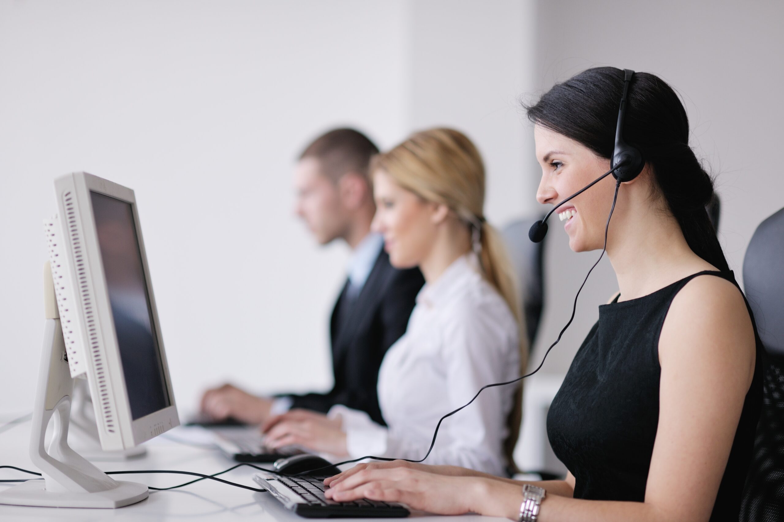 A woman wearing a headset and sitting at a computer