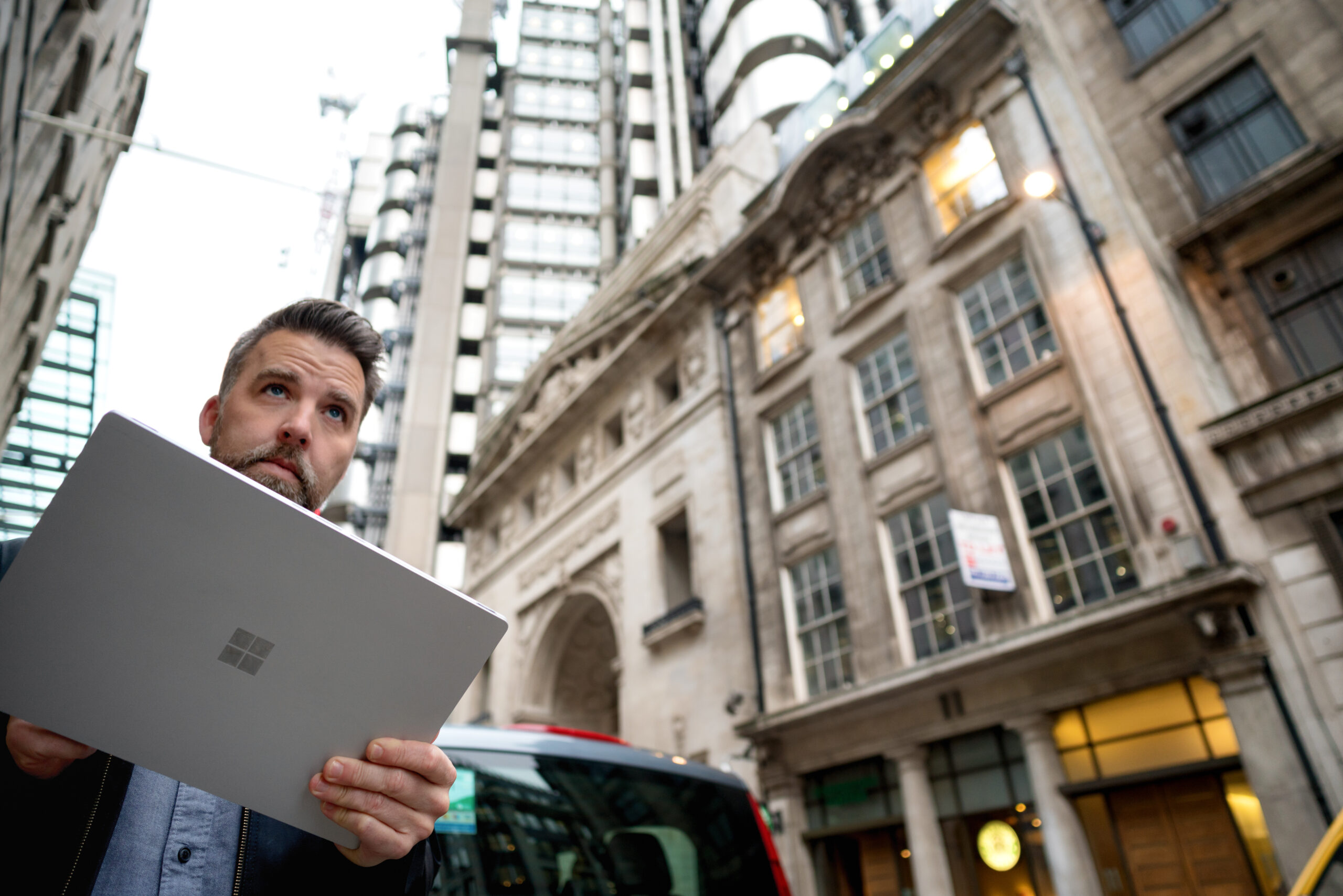 A man holding a laptop in front of a building