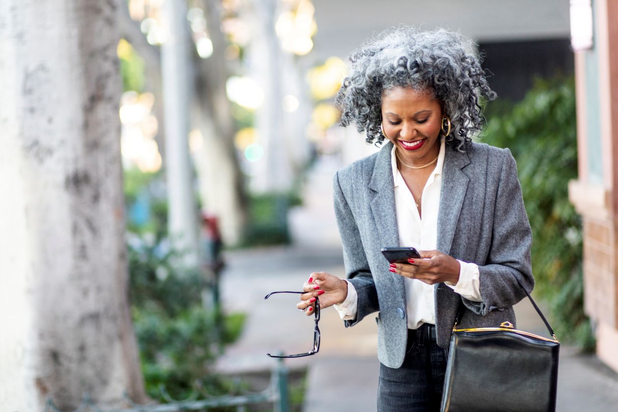 A business leader texting while walking in a city.