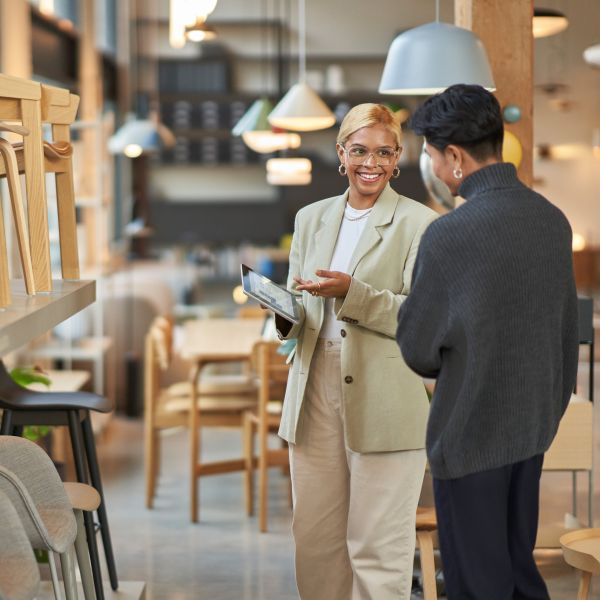 Retail store manager working with a customer, showing merchandise and providing customer service on-the-go using a tablet to locate inventory and place orders.
