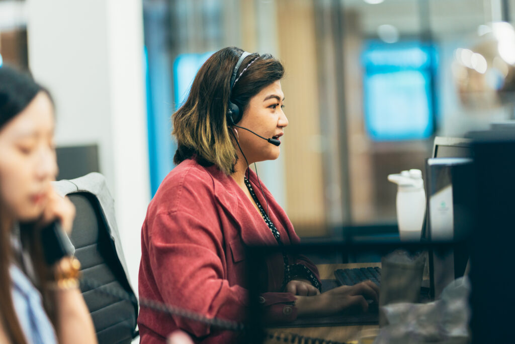 Person sitting in front of the computer wearing a headset with microphone.