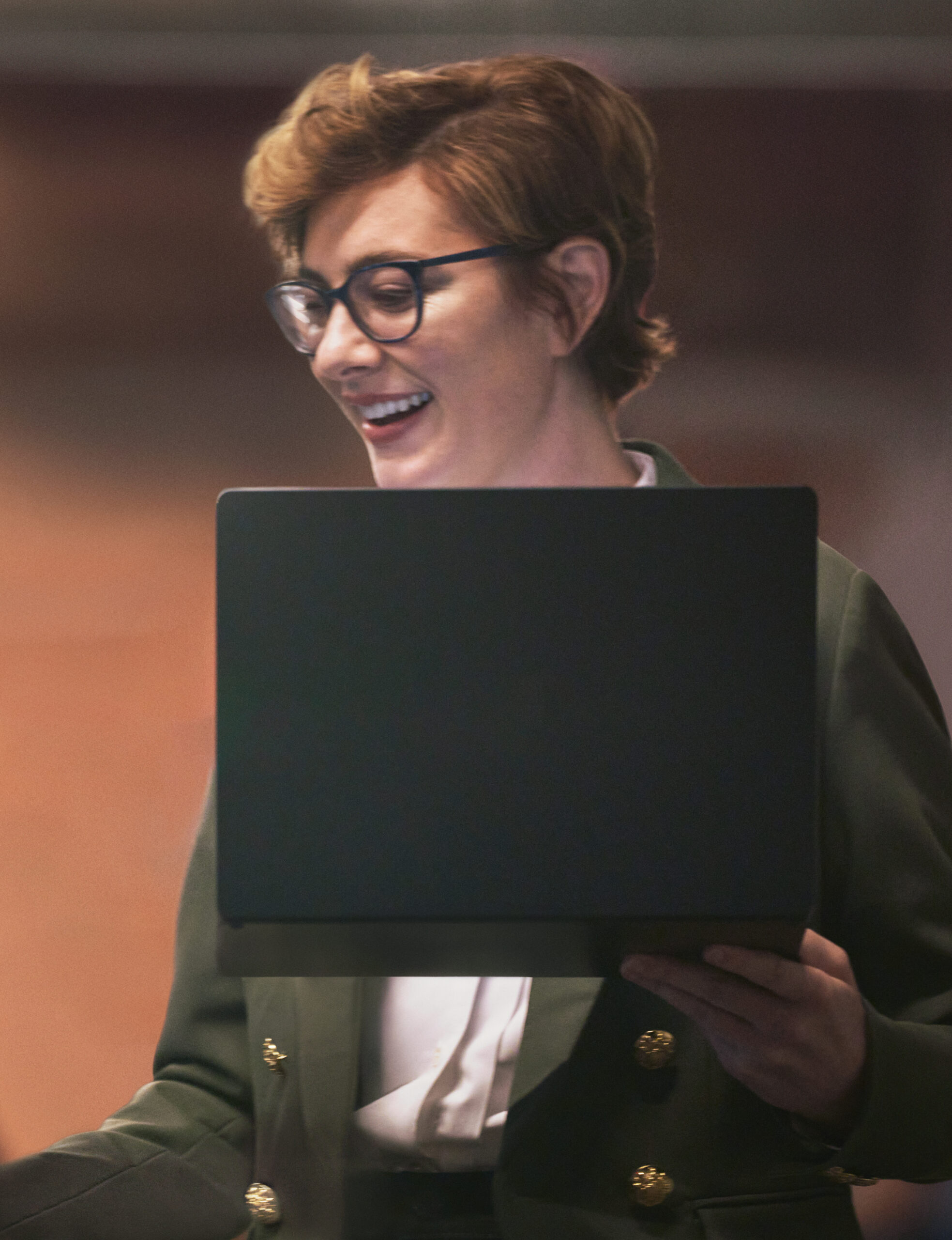 Smiling person holding a laptop