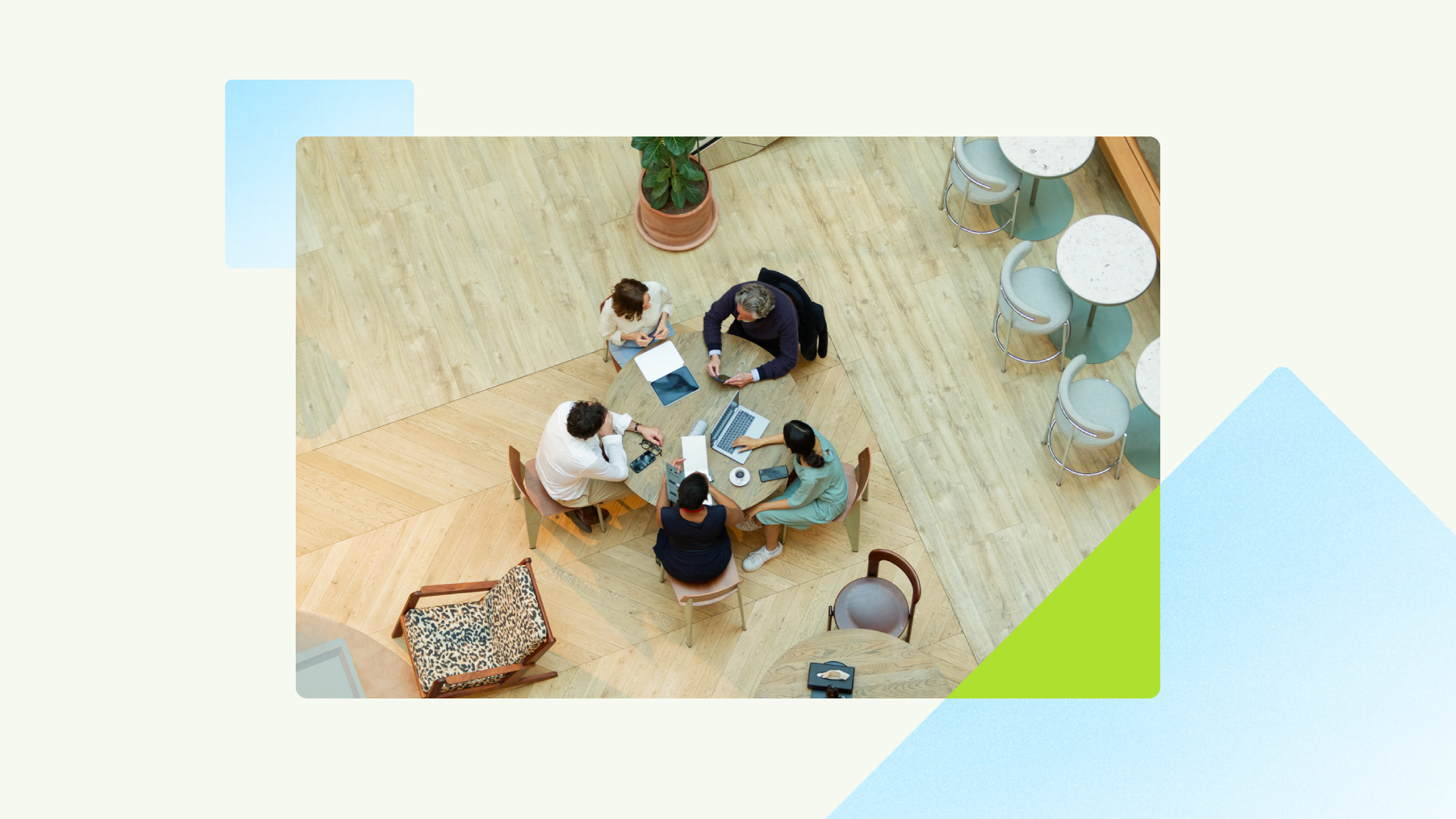 Overhead view of five people gathered around a table with a laptop, notebooks, and mobile devices in a modern workspace