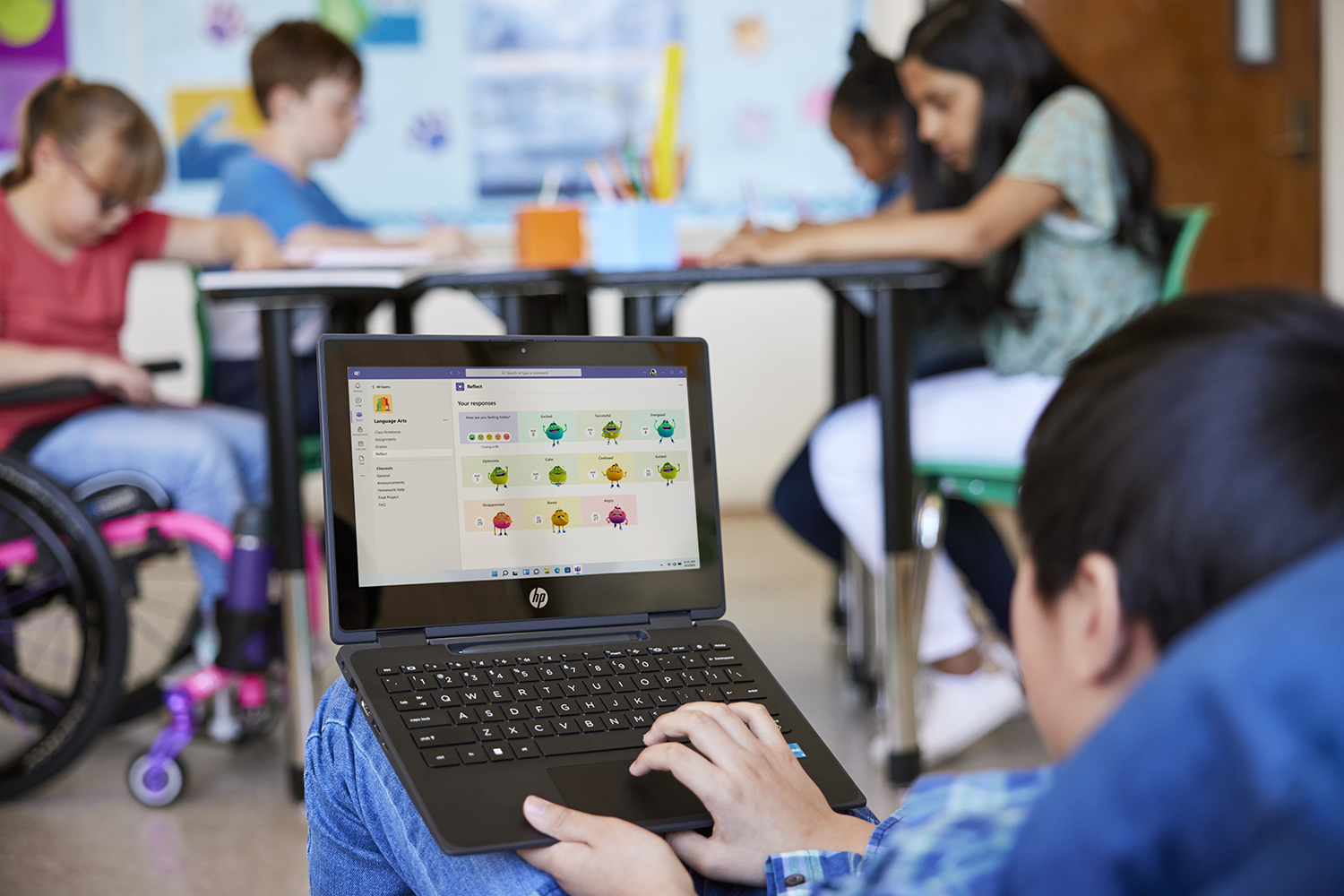 A student interacting with Microsoft Reflect on a laptop, as a group of students work nearby at a desk.