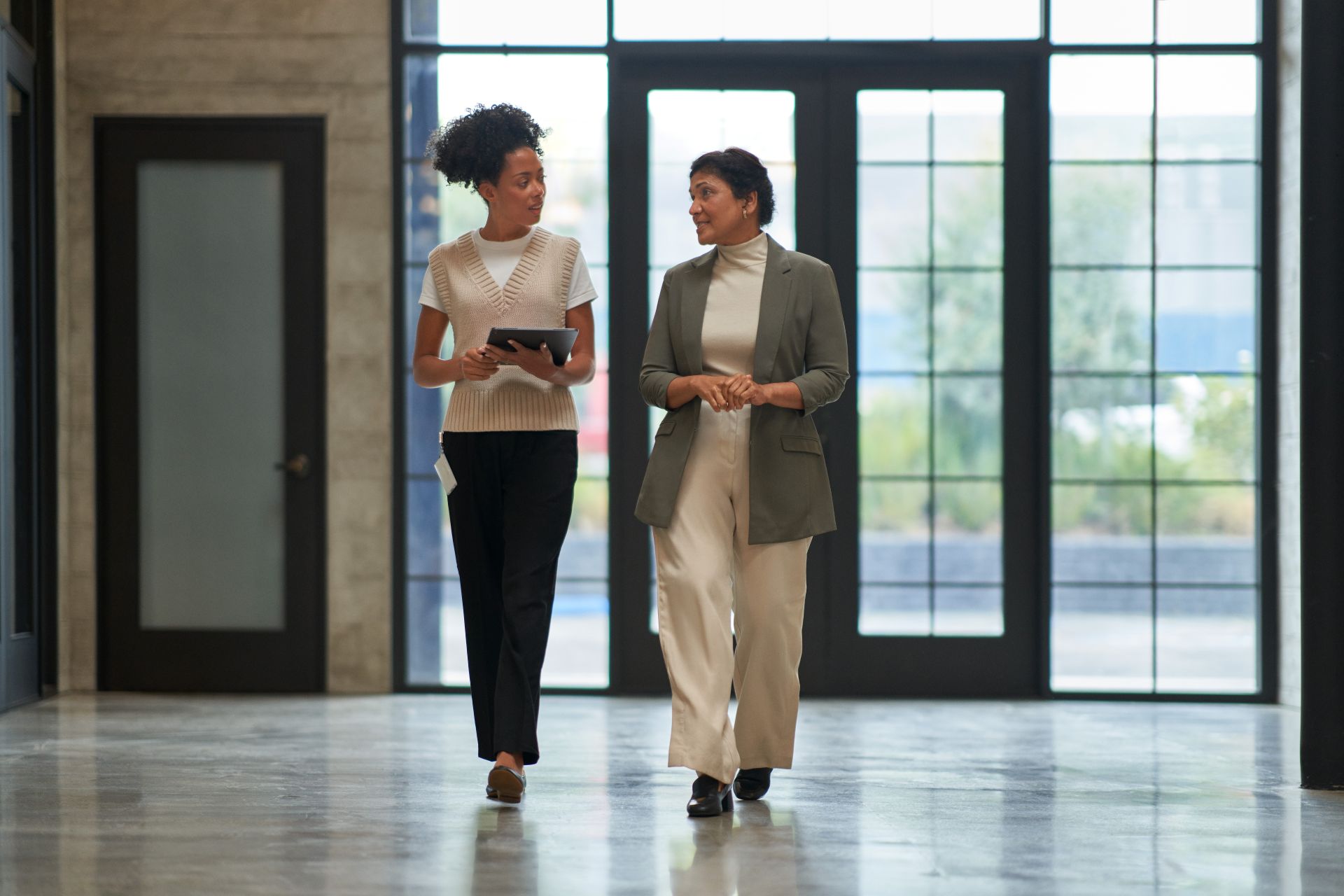 Two education leaders talking together while walking down a school hallway.