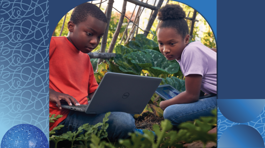 Two students sit in a garden together and work on a project on their laptops.