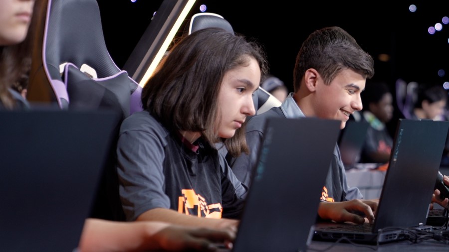 Decorative. Students on a stage at a conference playing a game on laptops.