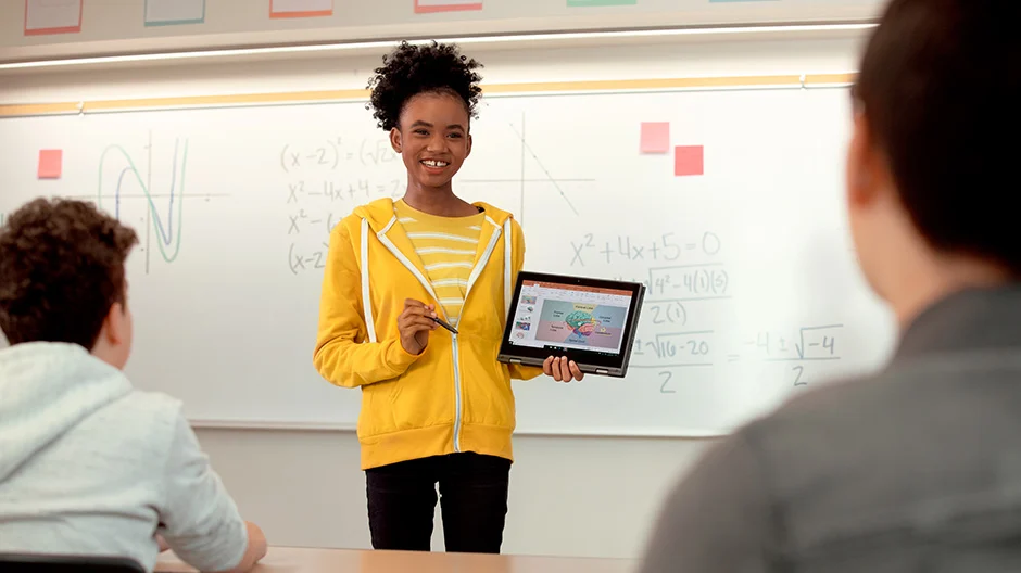 Student presenting in front of a class holding a tablet.