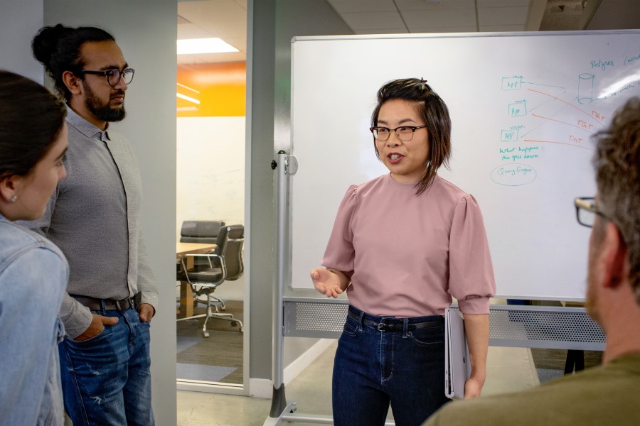 A female IT professional addressing a team in a meeting room at an educational institution.