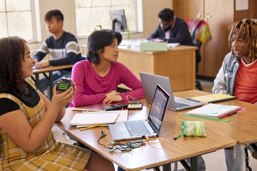 Three students work on a STEM project together in a school classroom.