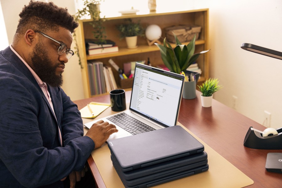 An IT professional works on a laptop at a desk in an office at an education institution.