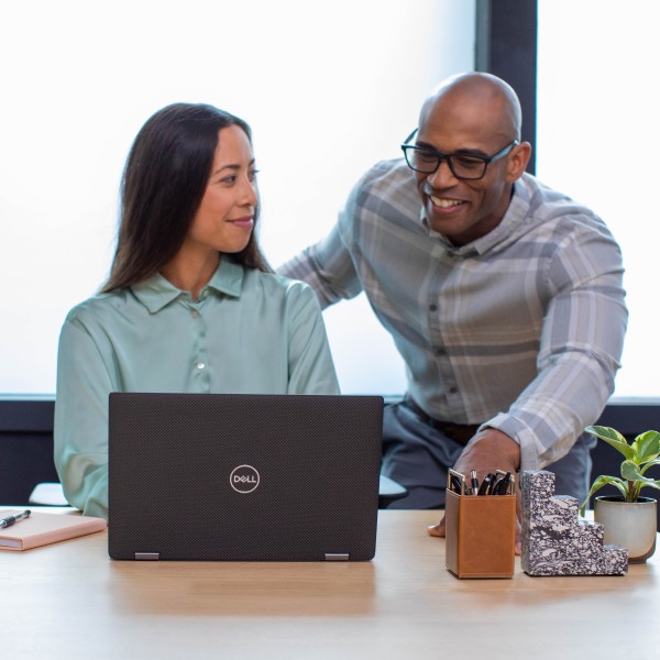 Two IT professionals looking at a laptop together in an office at an education institution.