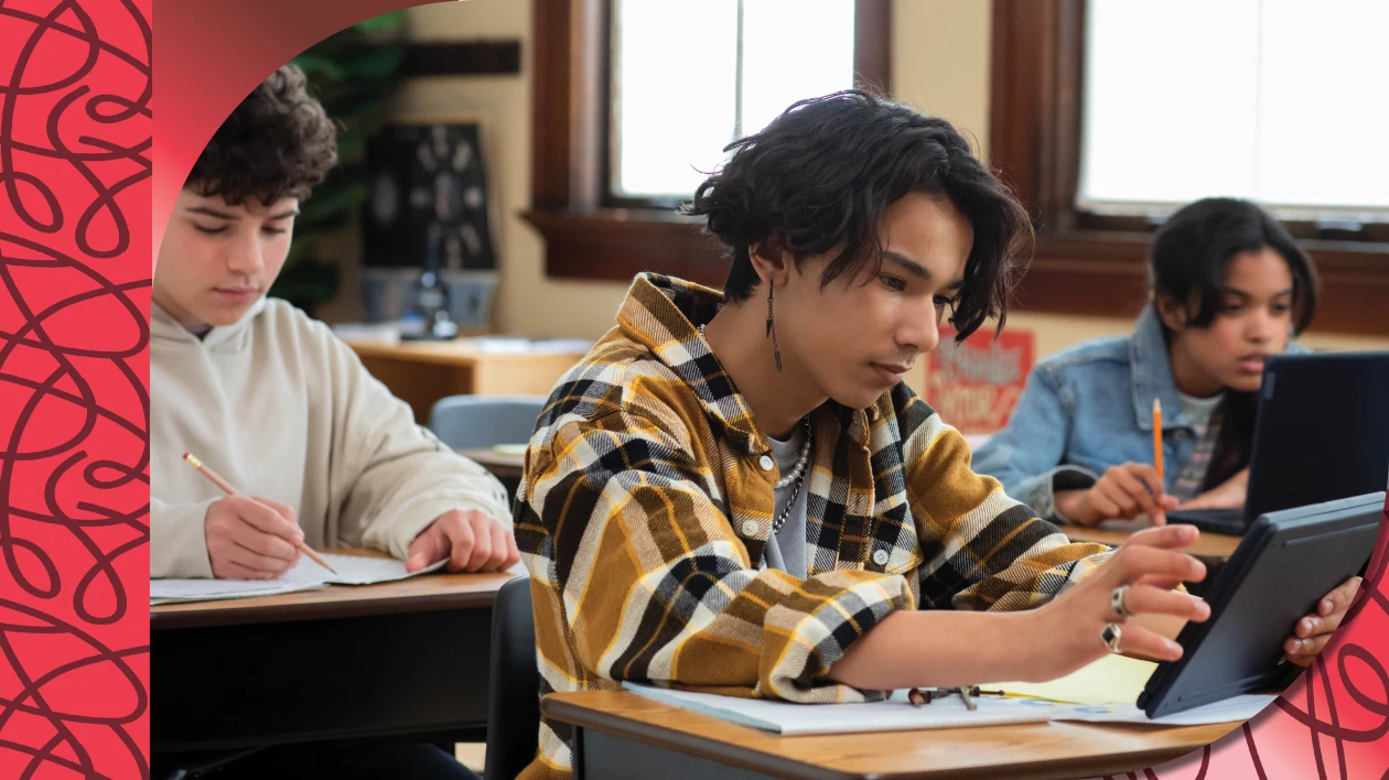 Students sitting at their desks in a classroom working on laptops