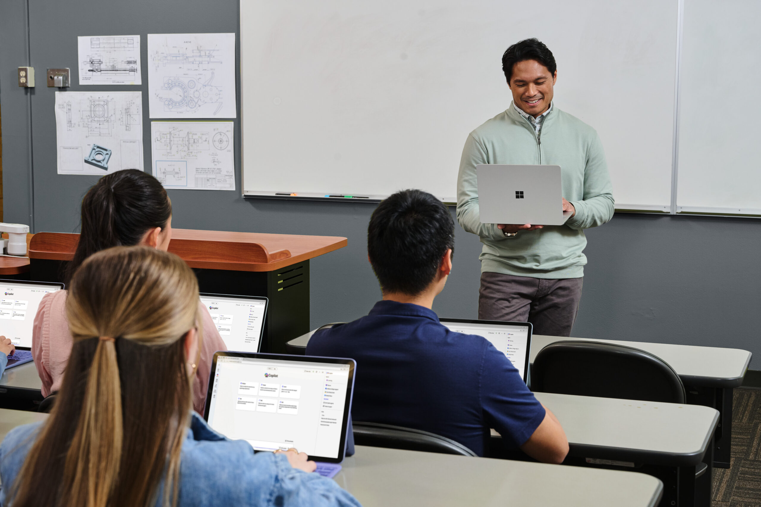 Teacher uses laptop in classroom.