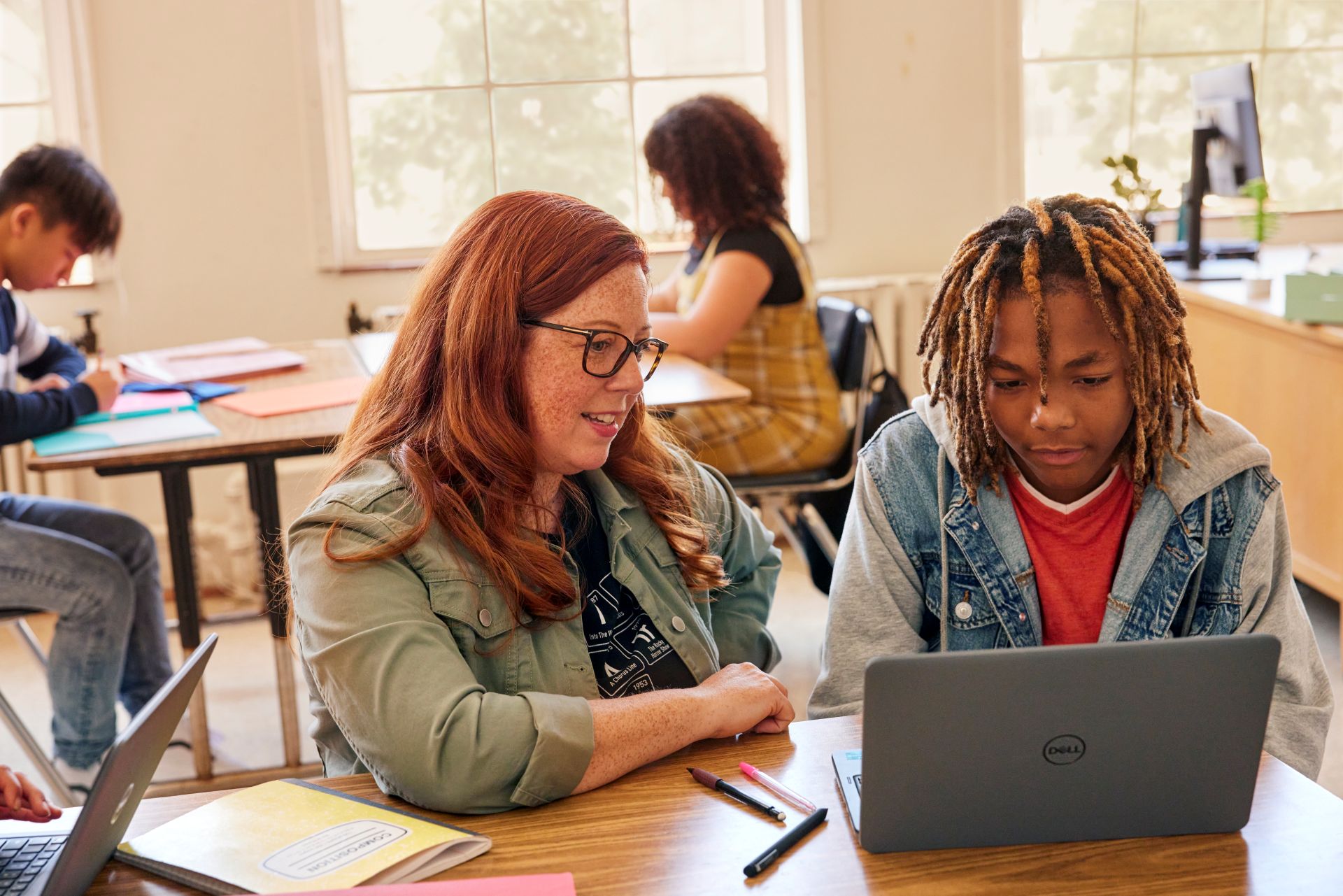 Teacher and student working on a laptop in a classroom
