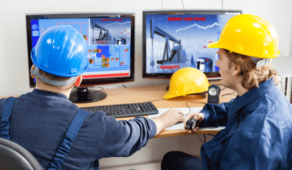 Two people wearing construction hats looking at a computer screen at Rockwell Automation