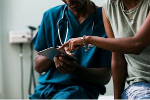 A doctor showing a patient information on a tablet computer.