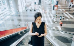 Woman on her phone riding up escalator