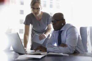 Two people working at laptop in office