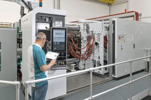 Man working in factory using a device to perform maintenance on machine
