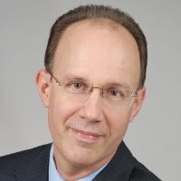 a man wearing a suit and tie smiling at the camera