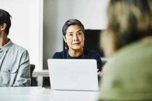 a man and a woman standing in front of a laptop