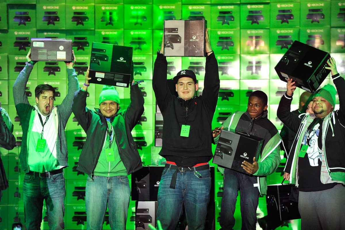 Happy Xbox One customers at a New York Launch event, holding their new Xbox products and smiling”