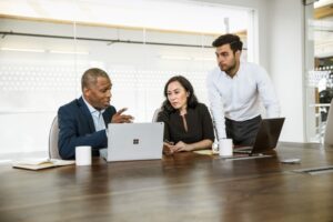 Group of people sitting at a desk in front of a laptop
