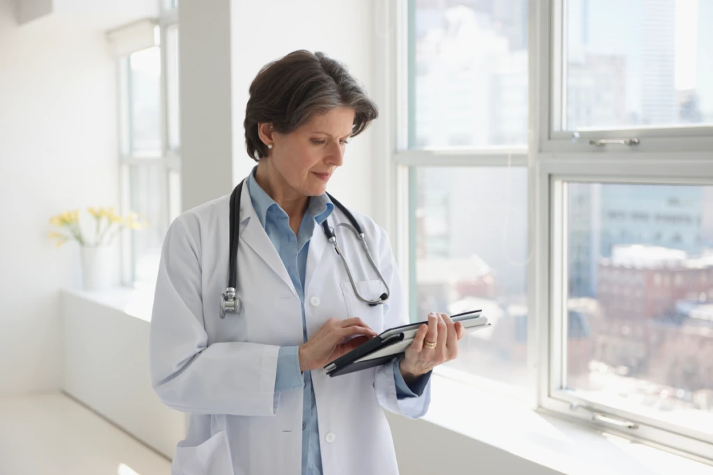 A woman in a white coat using a tablet