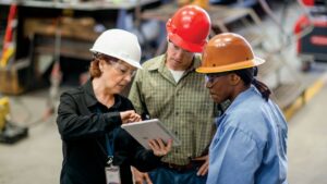 A group of people wearing hard hats looking at a tablet