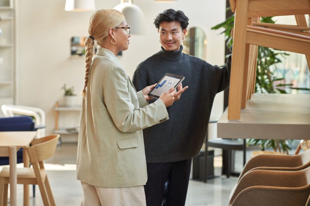 Retail store manager working with a customer, showing merchandise and providing customer service on-the-go using a tablet to locate inventory and place orders.