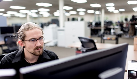 Ein junger Mann sitzt hinter seinem Bildschirm