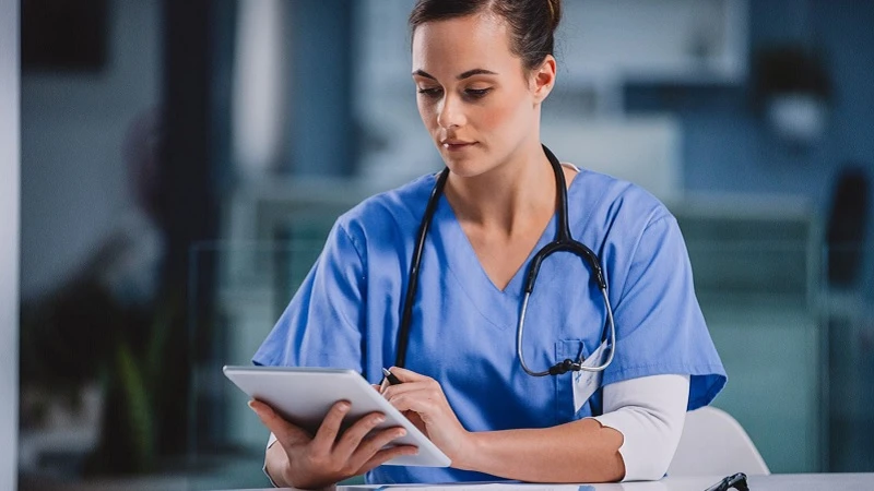 Eine &Auml;rztin im blauen Kittel bei der Arbeit an einen Tablet PC