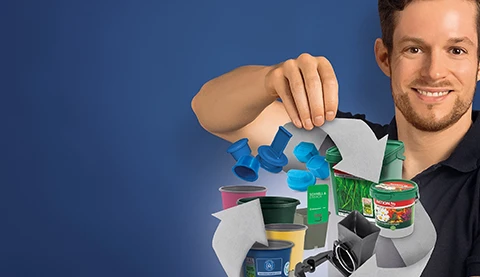 Mann hält ein Recycling Symbol mit verschiedenen Gegenständen aus Plastik