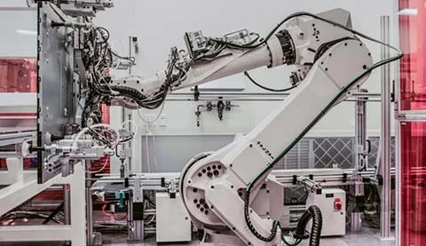 Ein wei&szlig;er Industrieroboter, der gerade etwas Flaches hochhebt. 