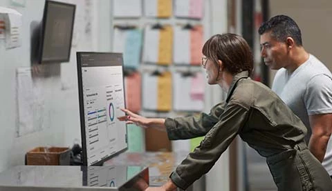 Zwei Menschen vor einem gro&szlig;en Tisch Bildschirm wobei eine Frau etwas erkl&auml;rt.