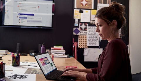 Eine Frau sitzt an einem Tisch und arbeitet an einem Laptop 