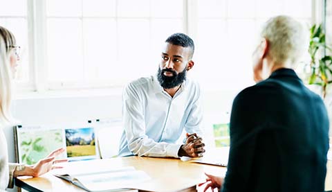 Drei Personen an einem Besprechungstisch.
