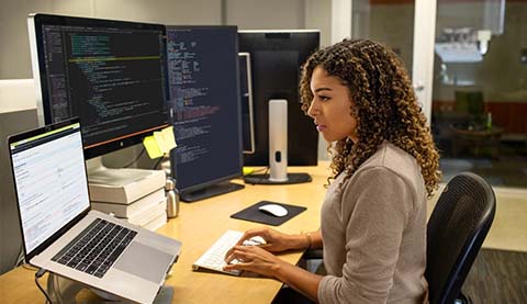Eine Frau sitzt an einem Tisch und programmiert.